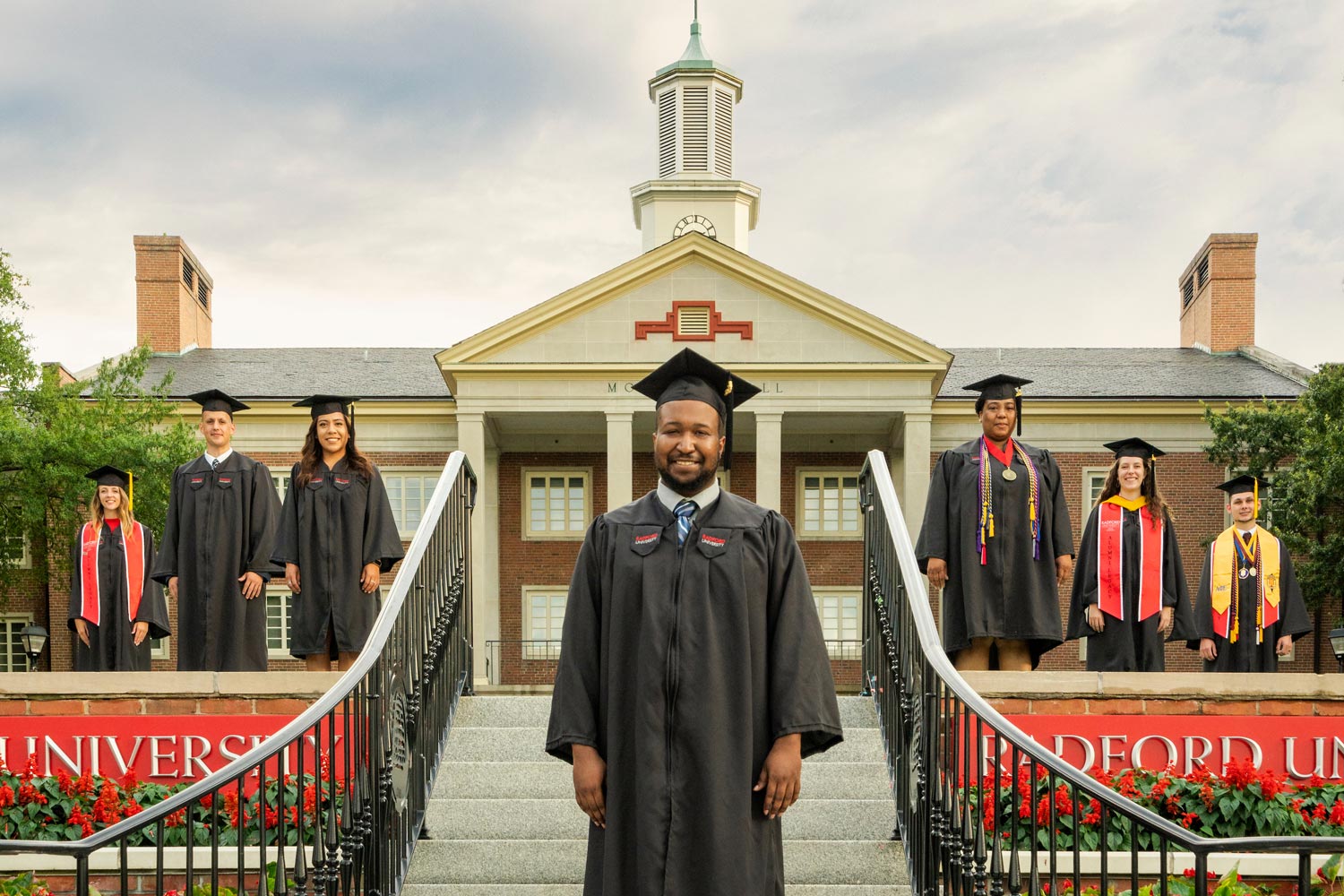 students on steps at Moffett Hall in commencement regalia