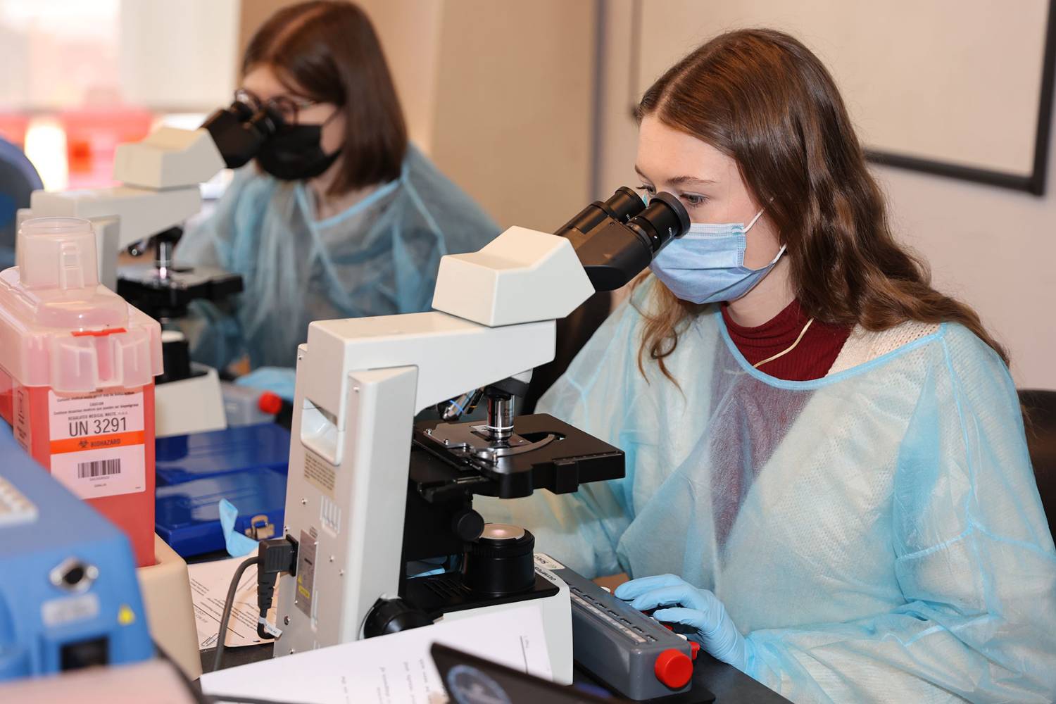 students in medical science lab looking through microscope