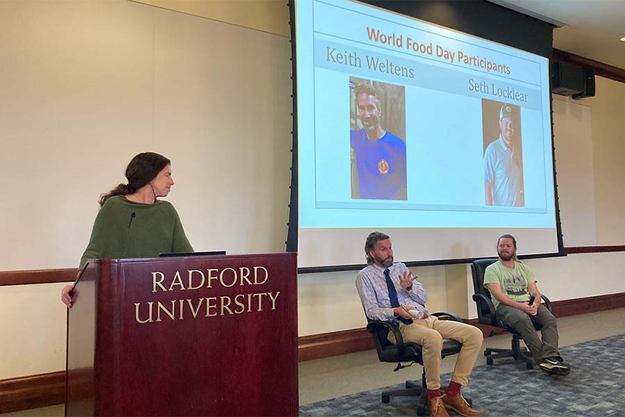 An instructor moderates from a podium while two local businessmen field questions from the audience about running breweries.