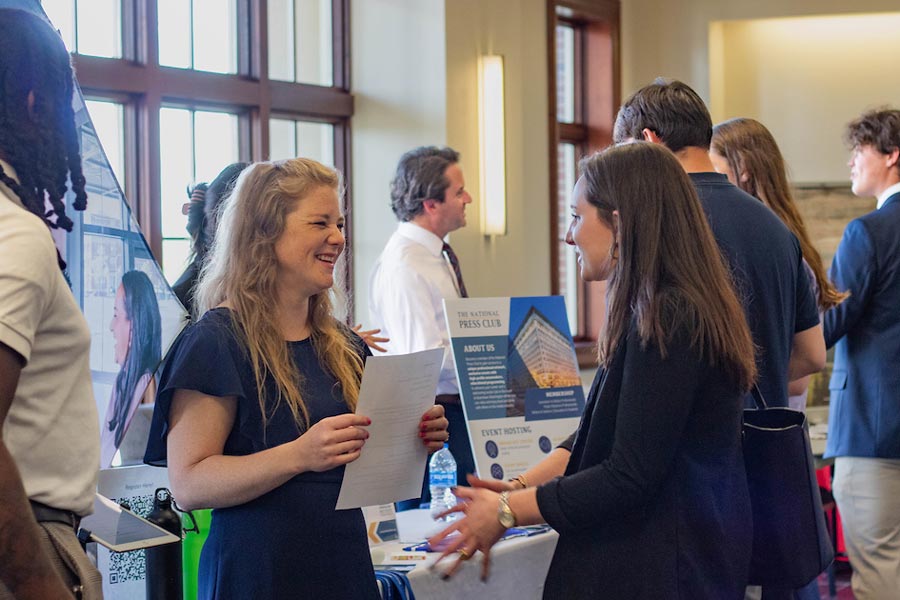 Two students at a job fair have a good-natured discussion.