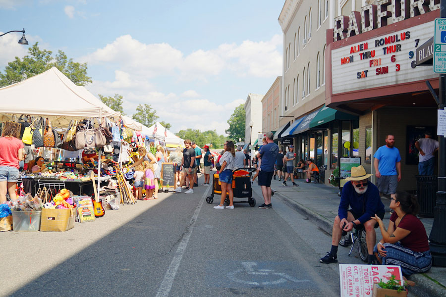 Lots of people line the streets looking at vendors who are selling merchandise on main street in Radford.