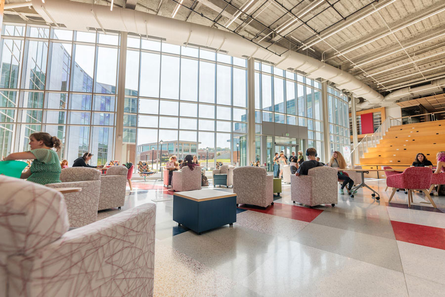 An interior shot of the main corridor for Radford University's Artis Center, depicting students seated and working at tables and sitting areas.