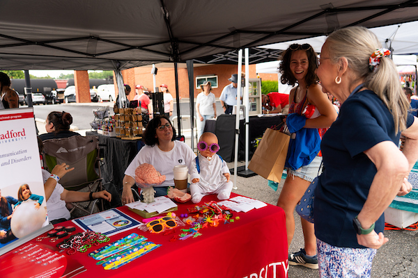 Participants at a booth during the Radford Community Fest talk and laugh together.