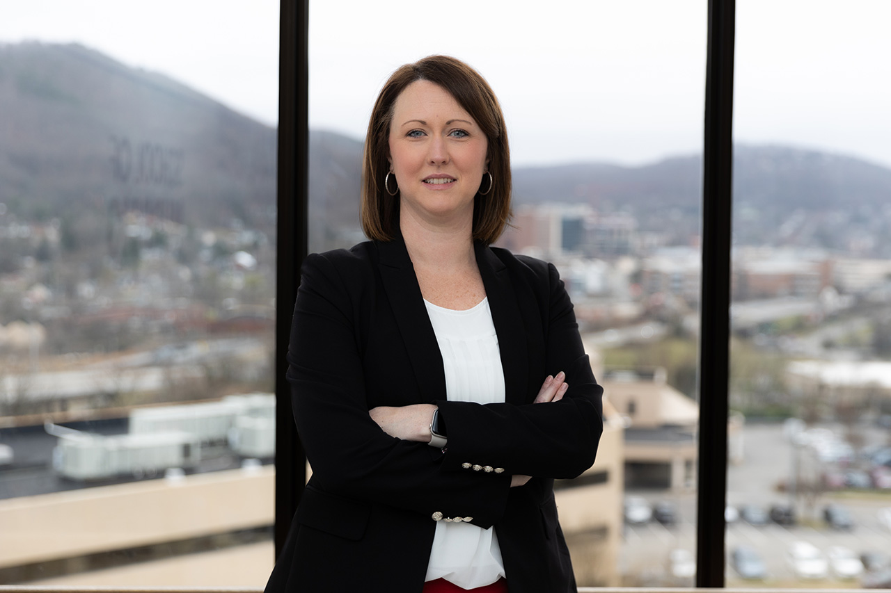 Jessica nichols stands with her arms folded smiling at the camera