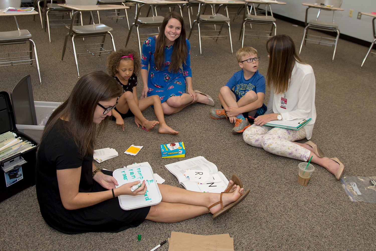 group of child and adults sitting in floor learning