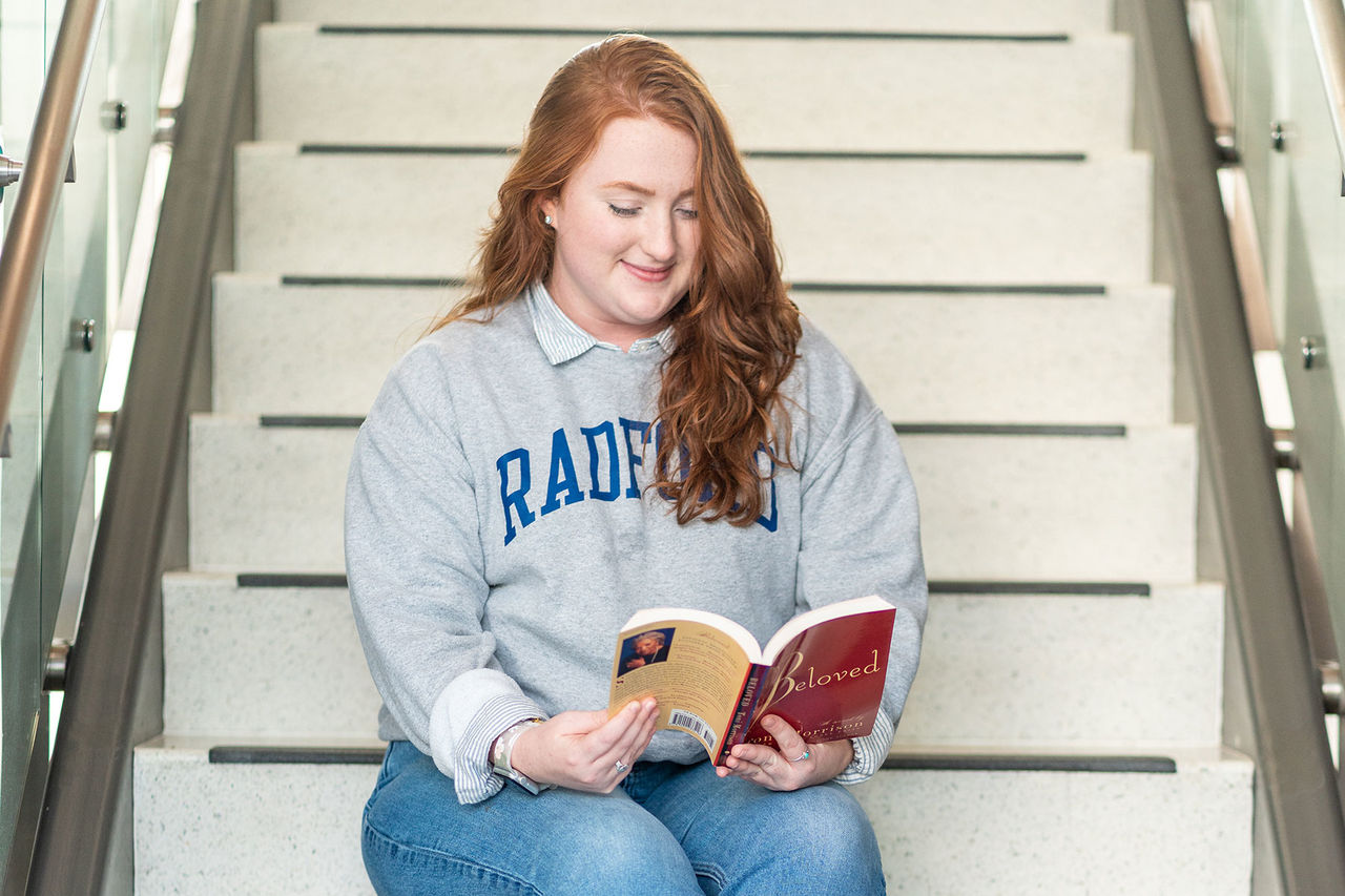 student reading a book on staircase