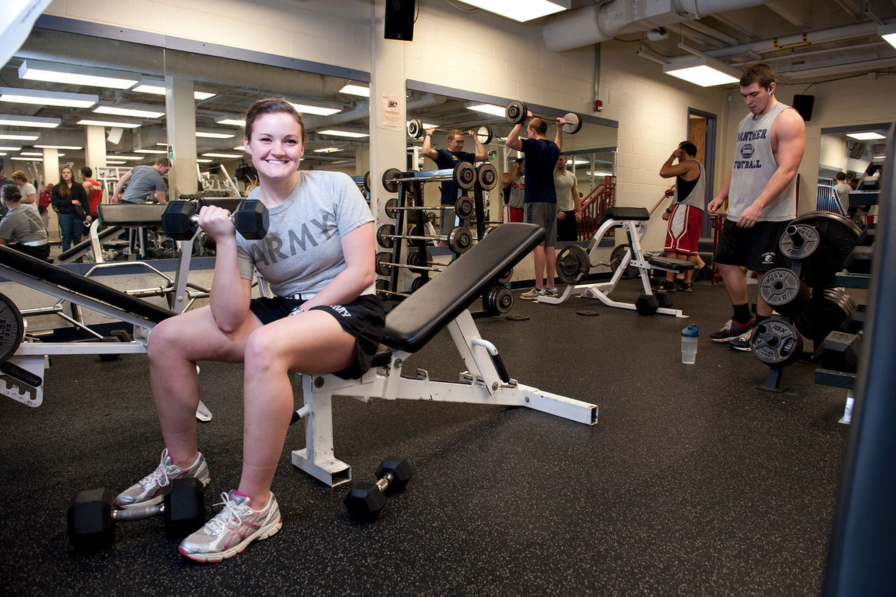 student lifting weight in gym