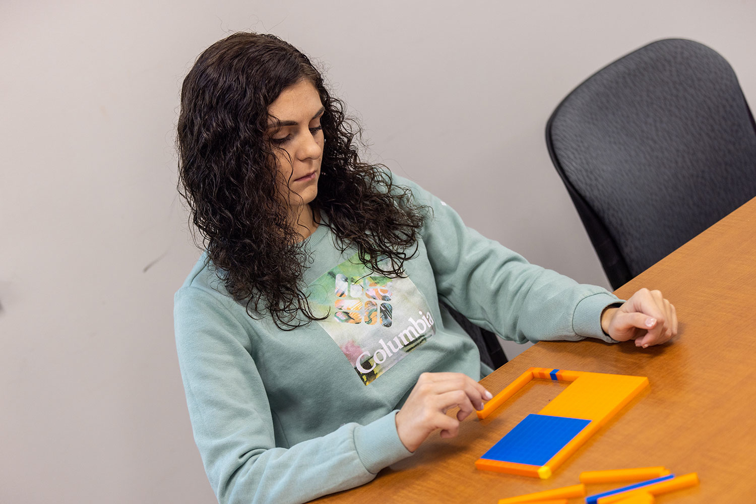 woman putting together a math like puzzle on a table