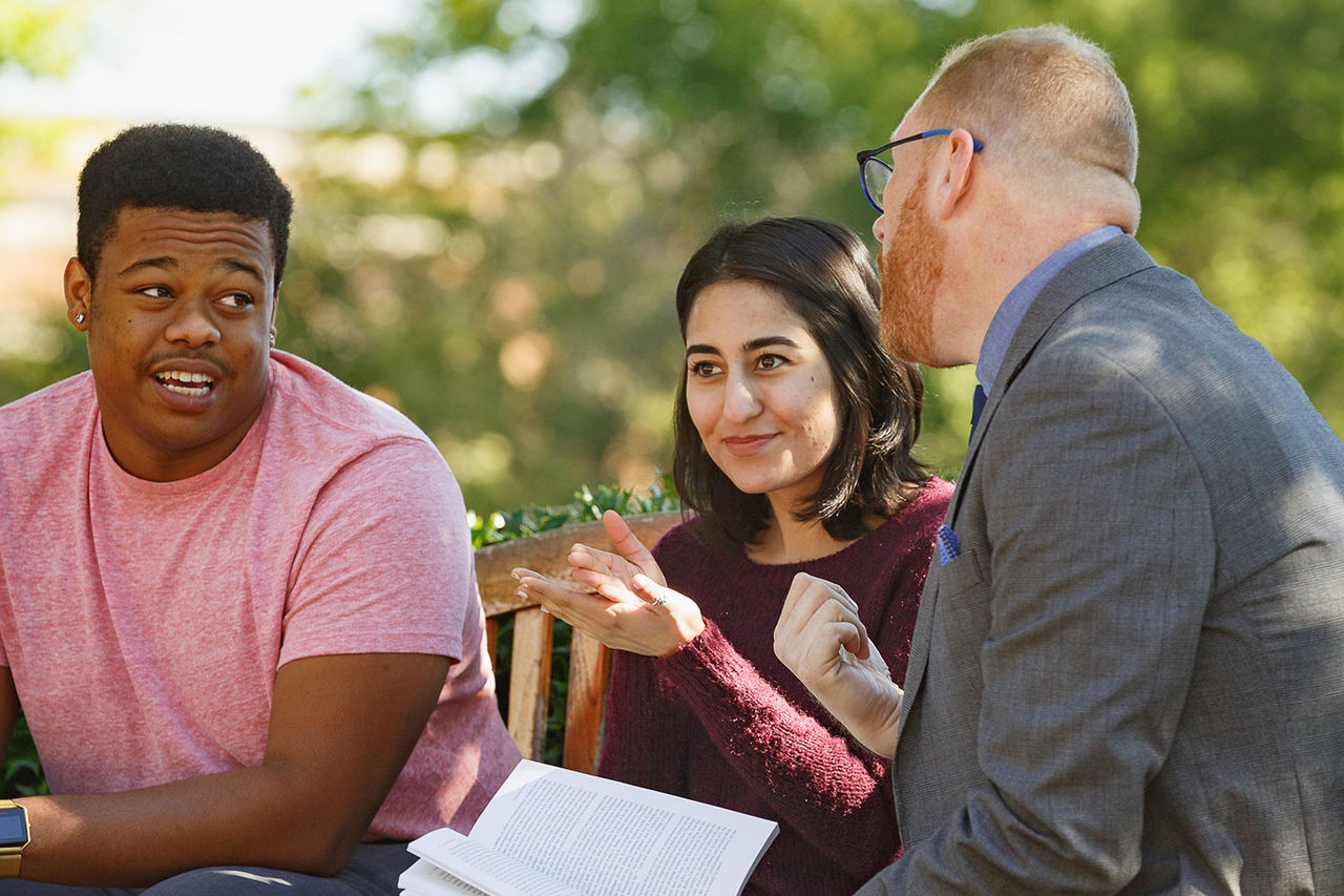 group of students having a discussion on a bench 