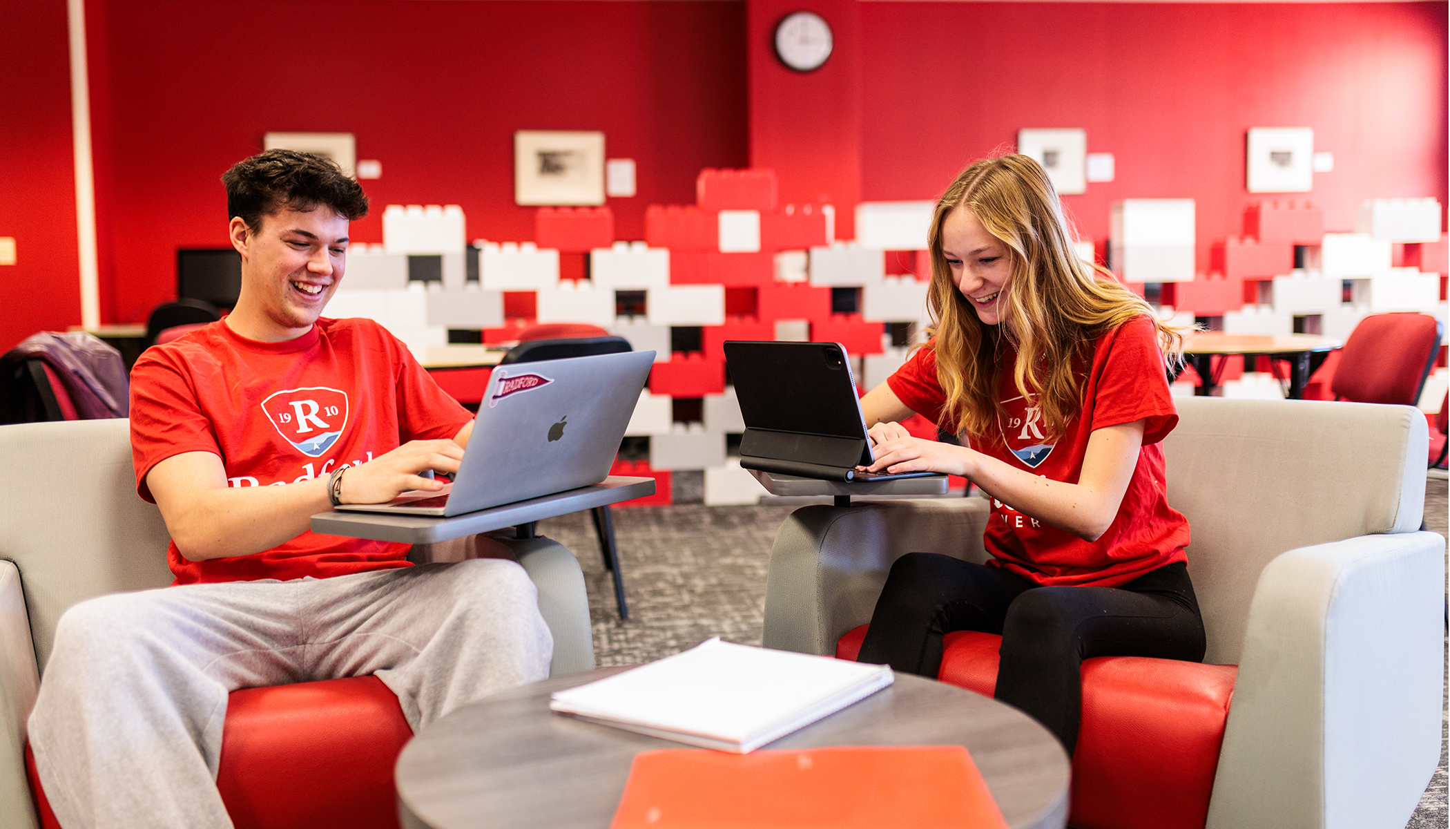 Students working on laptops in a lounge area.