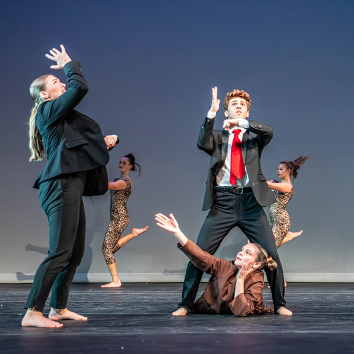 Dancers on stage in suits and ties.