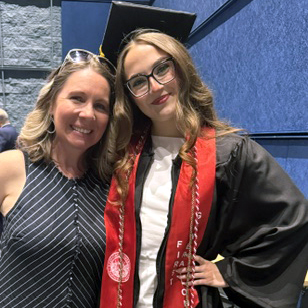 Professor Robyn Berg stands with graduate in cap and gown